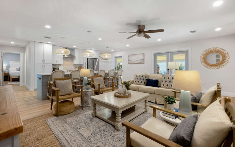 Relax in your spacious open-plan living area with coastal-inspired decor, modern kitchen, and comfortable seating perfect for gathering with loved ones.