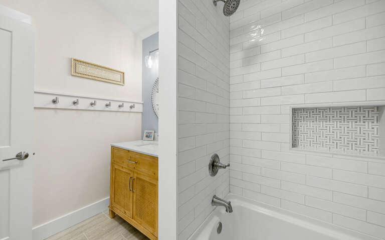 Unwind in your pristine bathroom featuring a luxurious subway-tiled tub-shower combo and charming natural wood vanity for all your essentials.