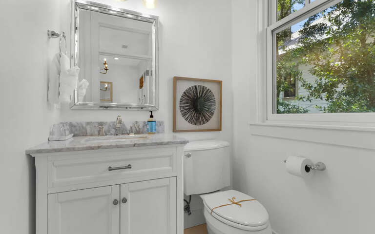 Refresh in your elegant powder room with marble countertops, crisp white cabinetry, and garden views that bring natural light into every moment.