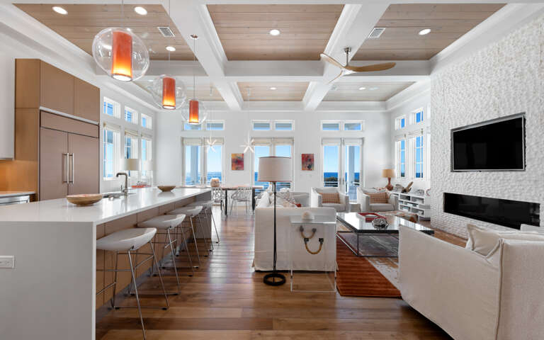 Relax in this stunning open-concept space where modern kitchen flows into elegant living area with fireplace and ocean views.