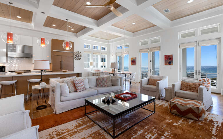 Relax in this stunning open-concept space where warm wood meets coastal elegance, with soaring coffered ceilings and breathtaking ocean views.