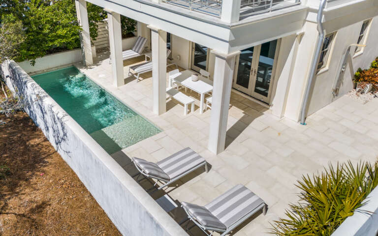 Elegant pool terrace with crisp white loungers and covered seating area perfect for your tropical retreat.