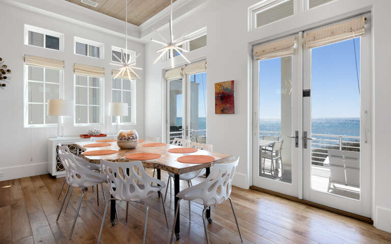 Gather around this stylish dining table where natural light floods through expansive windows, creating the perfect backdrop for memorable meals with sweeping views.