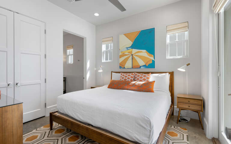 Relax in your bright bedroom featuring crisp white linens, colorful artwork, and thoughtful design touches that create a peaceful retreat.