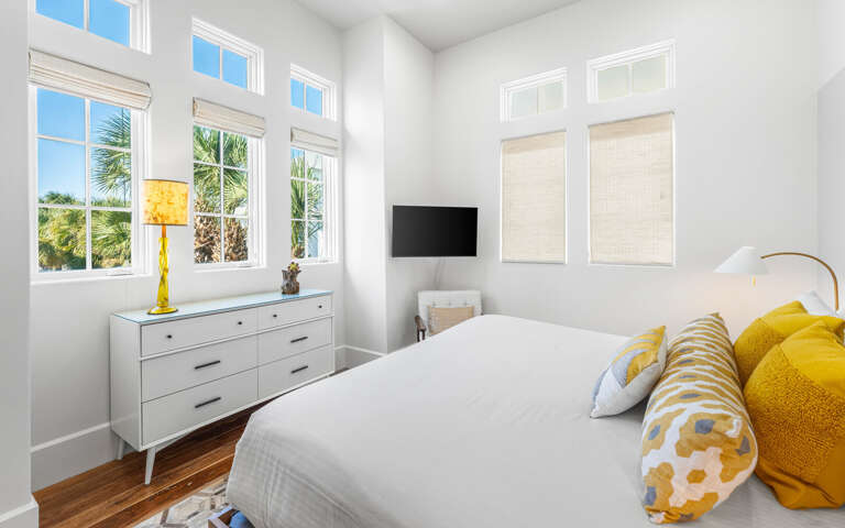 Sink into crisp white linens and sunny yellow accents in your bright bedroom, where tropical palm views frame peaceful mornings.