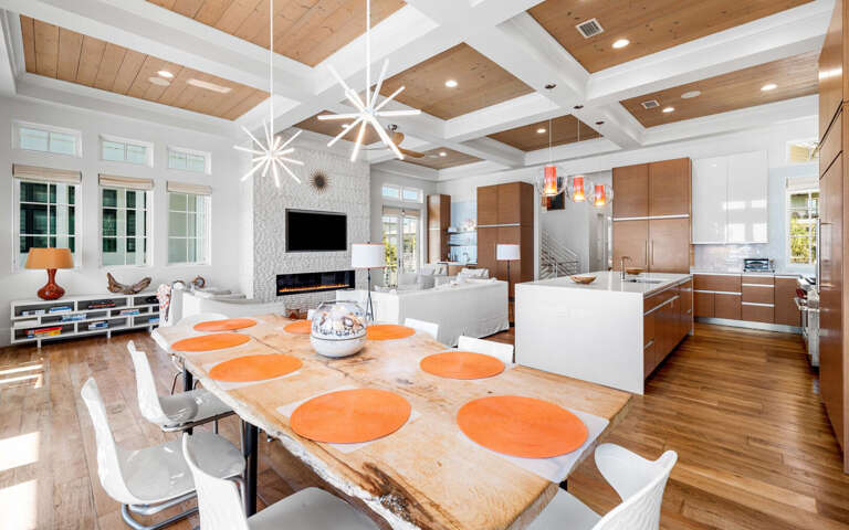 Step into your stunning open-concept living space where soaring wood-beamed ceilings create warmth above gleaming hardwood floors and modern furnishings invite relaxation.