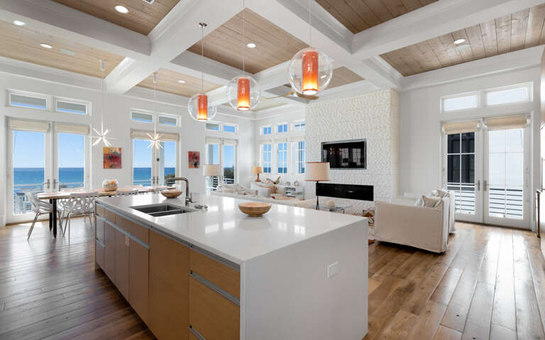 Your stunning open-concept space seamlessly blends kitchen and living areas, where modern pendant lights illuminate the sleek island and ocean views await.