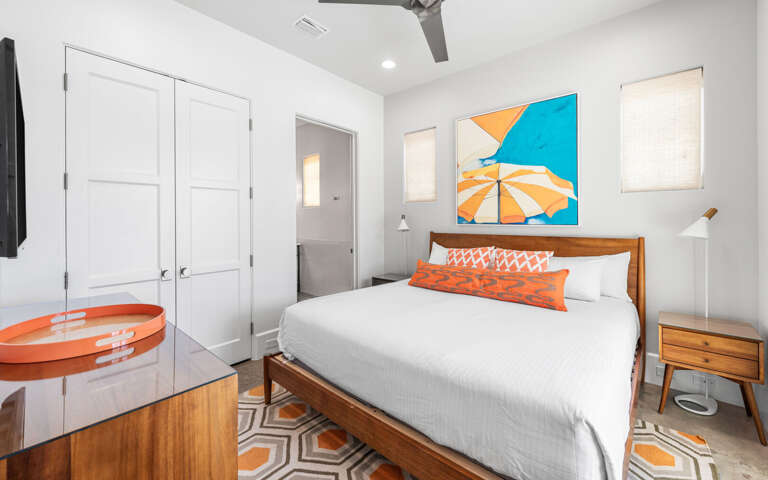 Your stylish bedroom features crisp linens, warm wood accents, and vibrant artwork creating a cheerful coastal vibe for restful nights.