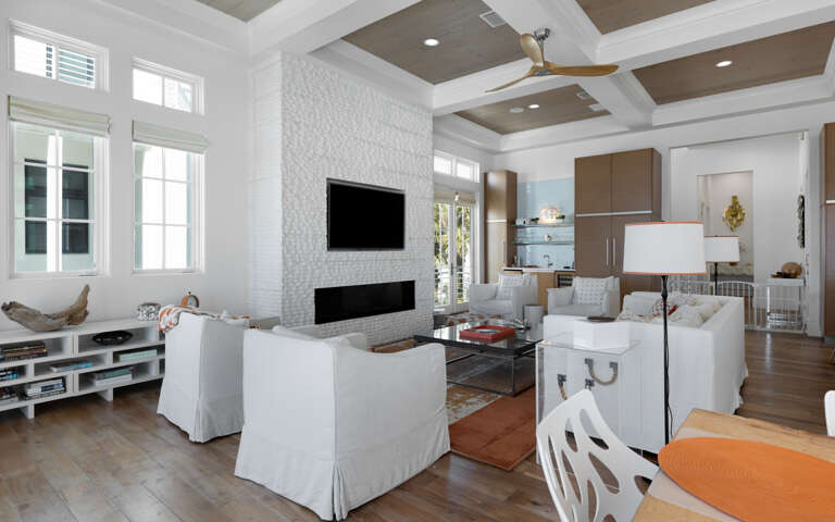 Unwind in your elegant living room featuring a cozy fireplace, modern entertainment center, and coffered ceiling that creates the perfect atmosphere for relaxation.