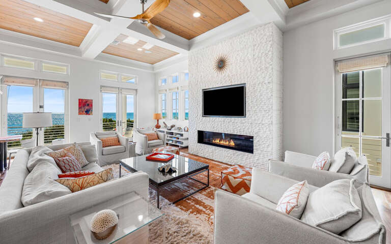 Unwind in this stunning living room where warm textures meet ocean views, complete with a cozy fireplace for evening ambiance.