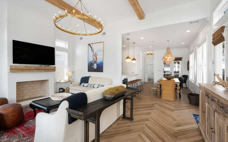 Unwind in this bright, open living space where coastal charm meets modern comfort with soaring ceilings and warm wood touches.