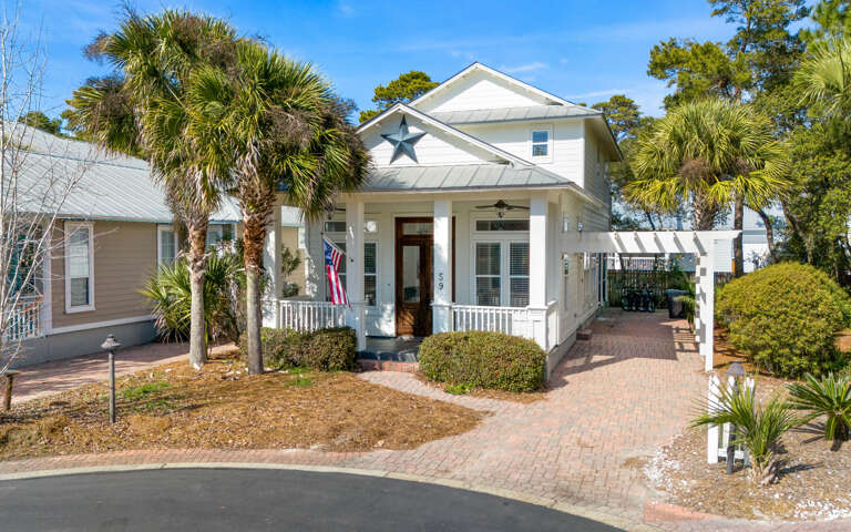 Charming coastal cottage with tropical palm trees and welcoming front porch creates the perfect beachside retreat setting.