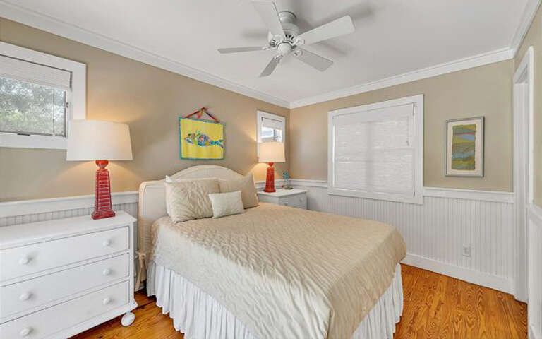 Drift off in your cozy coastal bedroom with warm natural light, ceiling fan comfort, and charming nautical touches throughout.