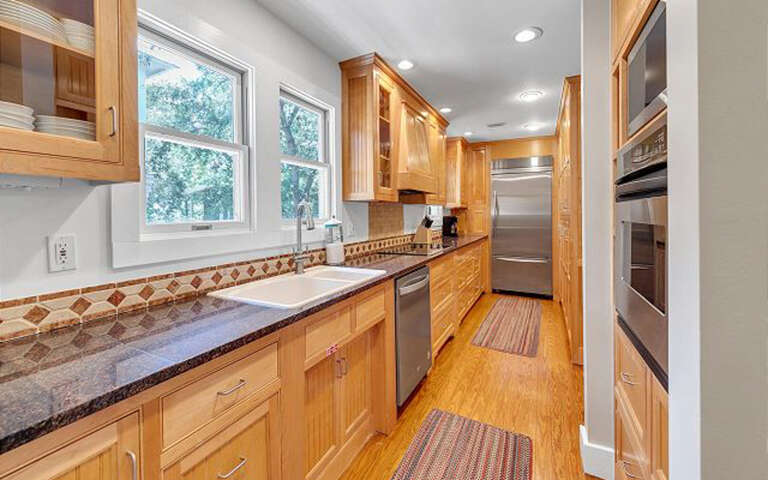 Your fully equipped galley kitchen features warm wood cabinetry, granite counters, and stainless appliances for creating memorable meals together.