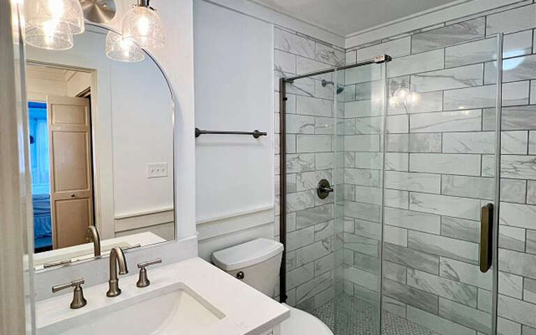 Luxurious marble bathroom with glass shower, elegant vanity, and stylish lighting awaits your relaxing getaway.