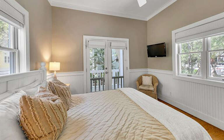 Wake up in your bright, airy bedroom with charming white wainscoting and private balcony access for morning coffee moments.