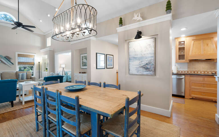Gather around your beautiful coastal dining table where blue chairs invite memorable meals beneath the statement chandelier.