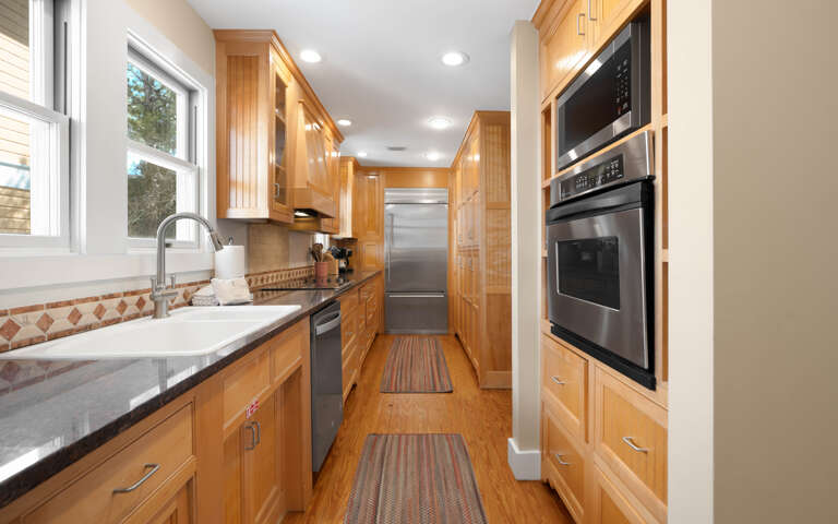 Your gourmet galley kitchen features warm wood cabinetry, granite counters, and premium appliances for memorable home-cooked meals.