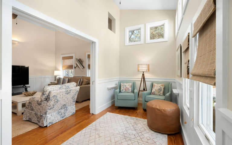 Settle into your cozy reading nook with twin aqua chairs and natural light streaming through windows.