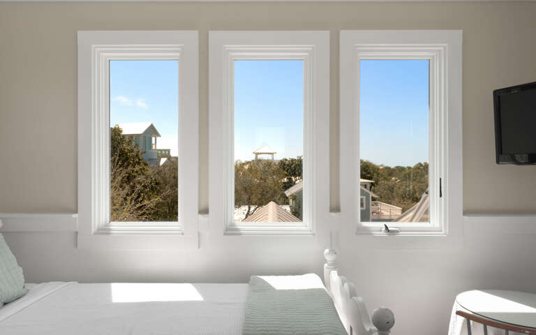 Wake up to peaceful mornings in your bright bedroom, where three picture windows frame leafy rooftops and blue skies.