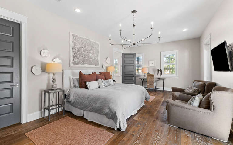 Unwind in your spacious bedroom sanctuary with plush bedding, cozy seating area, and modern chandelier creating the perfect retreat.