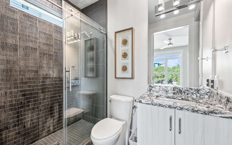 Your elegant bathroom features a glass-enclosed shower, marble vanity, and modern finishes for a luxurious retreat.