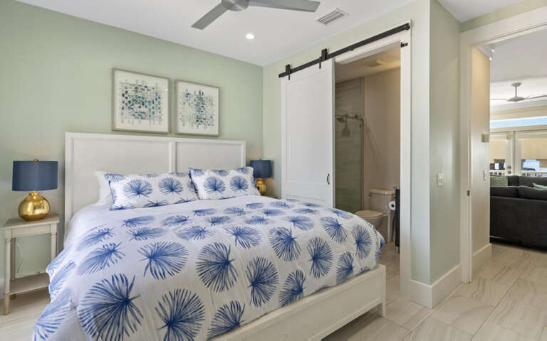 Your serene bedroom features tropical-inspired bedding and a private ensuite with stylish barn door for ultimate relaxation.