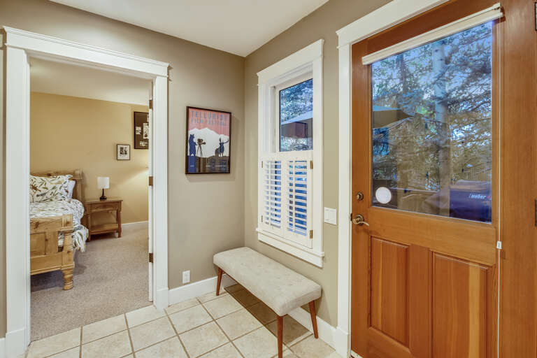 Mud room entrance leads to the back deck with BBQ and outside furniture at back of home