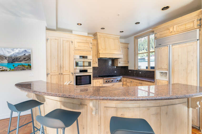 Open well equipped kitchen with Viking, Bosch and Thermodore appliances. Large counter with bar stools and wall mounted TV facing the living area seating. Open well equipped kitchen with Viking, Bosch and Thermodore appliances. Large counter with bar stools and wall mounted TV facing the living area seating.