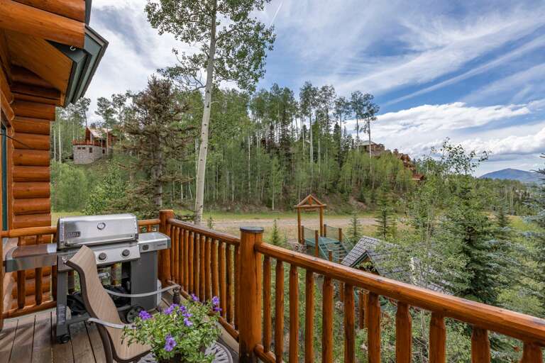 Kitchen deck with chairs, table and propane grill with views of the ski run.