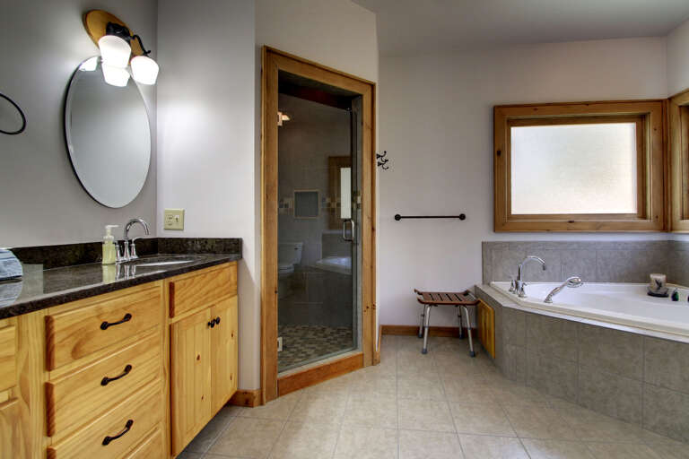 The master bath is adjacent to the Master Bedroom and offers a custom tile shower and a Jacuzzi Tub.  Double Bowls on the Granite Vanity Counter