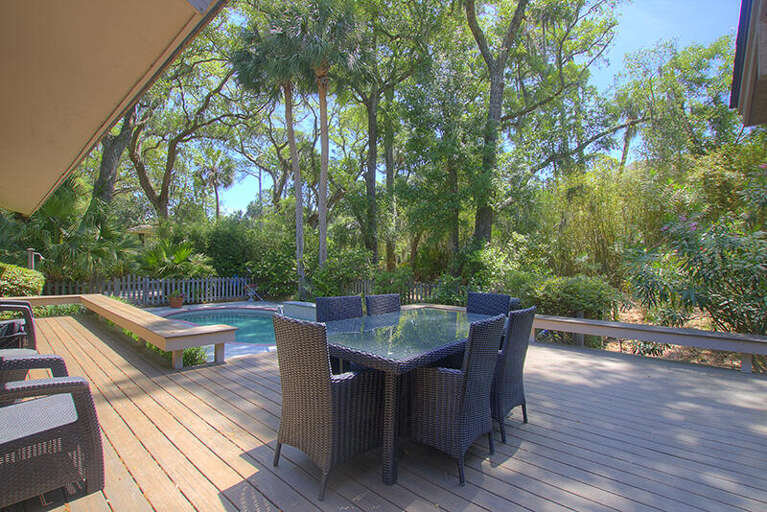 Shaded Deck Dining Beside Serene Pool, Lush Greenery Surrounds