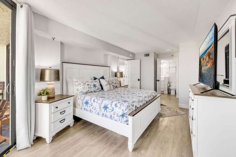 Spacious bedroom with a king bed, large TV, and a dedicated workspace with a desk and chair for