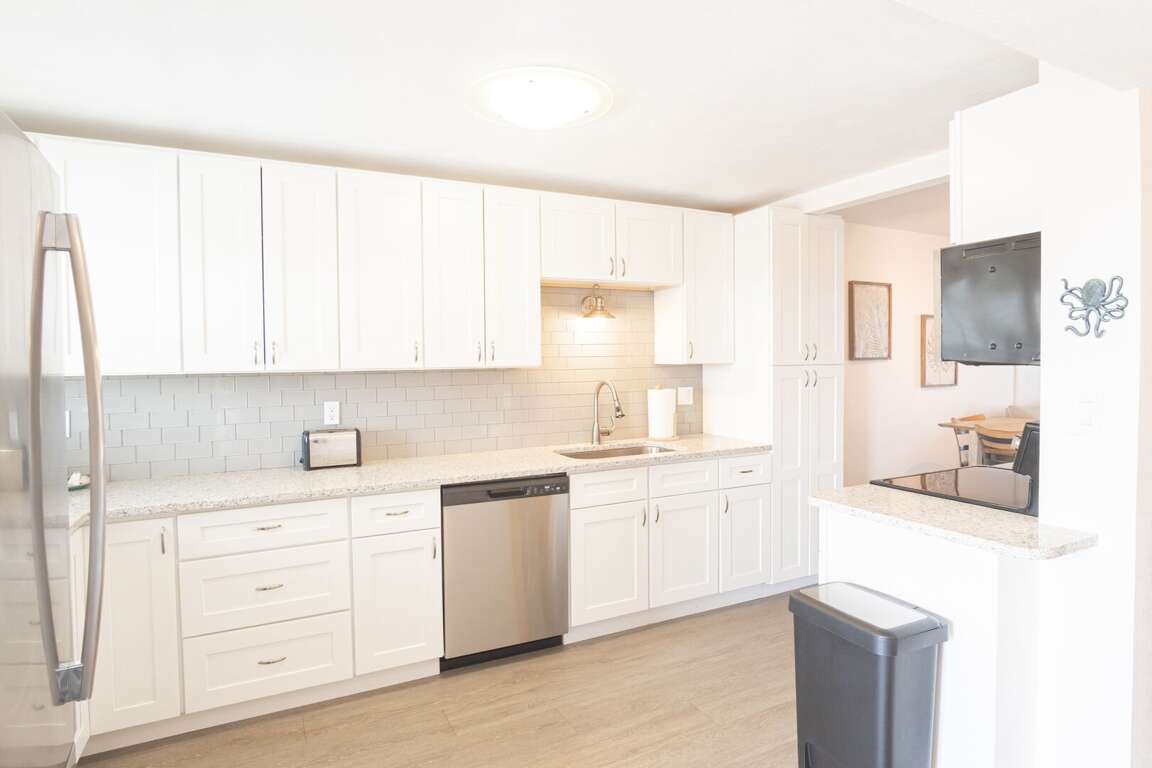 The kitchen is outfitted with sleek subway tiles and crisp white cabinets, offering a modern and clean space to cook and gather The kitchen is outfitted with sleek subway tiles and crisp white cabinets, offering a modern and clean space to cook and gather