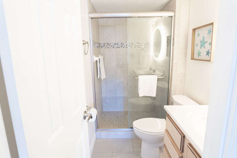 Master bathroom featuring an updated glass and tile shower, complemented by sleek lighted mirrors for a modern touch Master bathroom featuring an updated glass and tile shower, complemented by sleek lighted mirrors for a modern touch