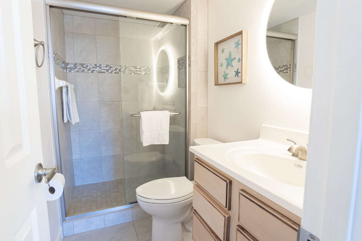 Master bathroom with a sleek glass and tile shower, complemented by lighted mirrors and plush spa-quality towels for a truly relaxing experience Master bathroom with a sleek glass and tile shower, complemented by lighted mirrors and plush spa-quality towels for a truly relaxing experience