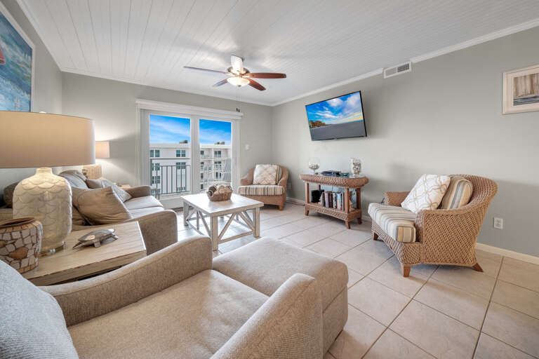 Relax in the modern living room at Sea Coast Gardens II 508, featuring plenty of comfortable seating and a mounted cable TV for ultimate entertainment Relax in the modern living room at Sea Coast Gardens II 508, featuring plenty of comfortable seating and a mounted cable TV for ultimate entertainment