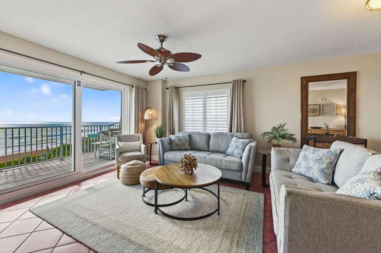 The direct oceanfront living room offers corner condo views, cozy seating, and a flatscreen TV for laid-back beach days