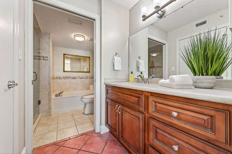 The ensuite master bathroom features a spacious tub and updated tile shower for a spa-like beach retreat
