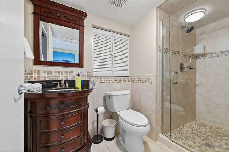 The updated guest bathroom features a sleek glass and tile shower for a fresh, modern feel
