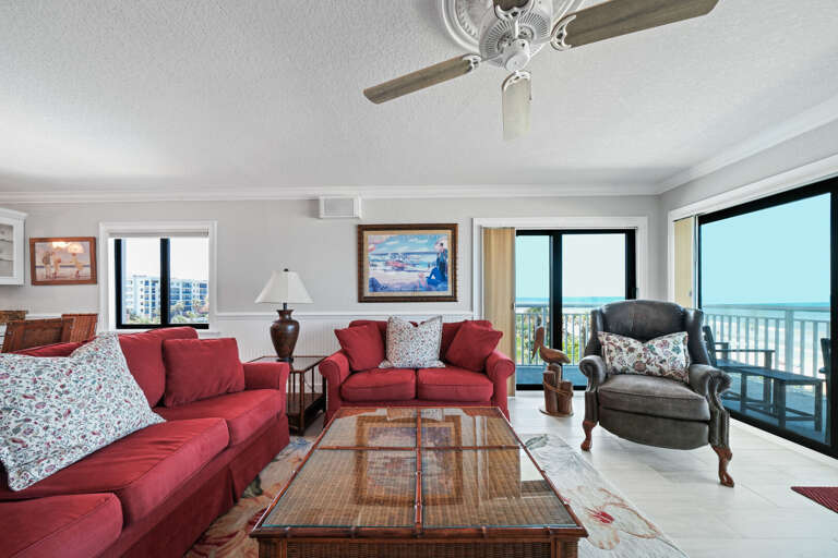 Bright, beachfront living room with ample seating and stunning views of the pool and ocean