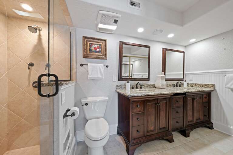 Luxurious master bathroom with granite countertops and a sleek glass and tile shower
