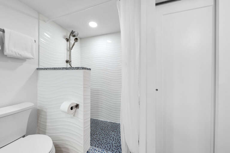 The master bathroom features an updated tile shower with a relaxing blue and white color palate