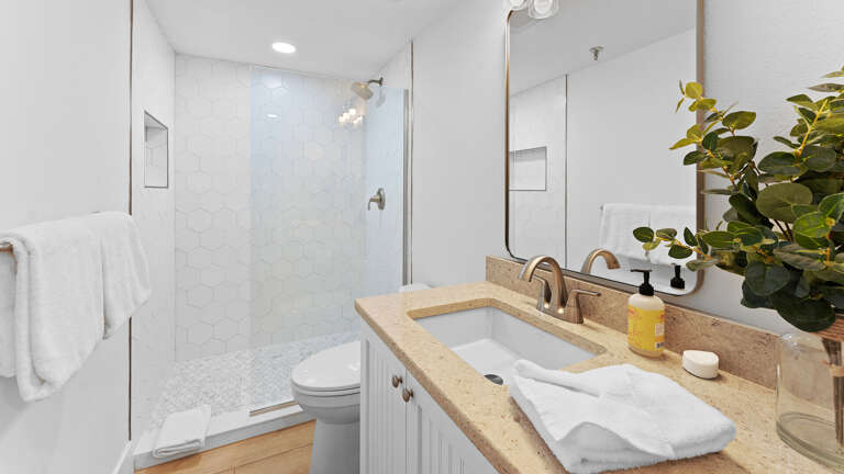 Fresh and modern, the updated guest bathroom features a sleek glass and tile shower