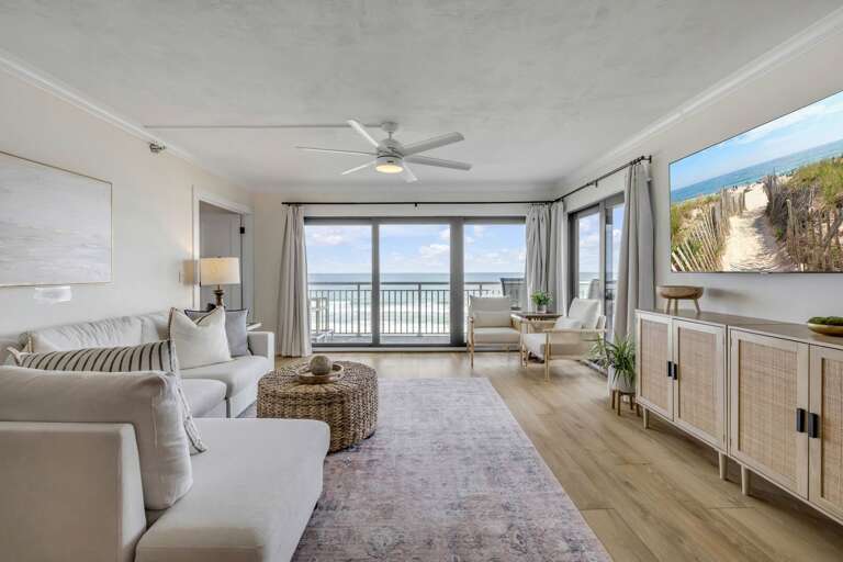 Relax in the oceanfront living room, featuring a mounted cable TV for your entertainment while enjoying the stunning views of New Smyrna Beach