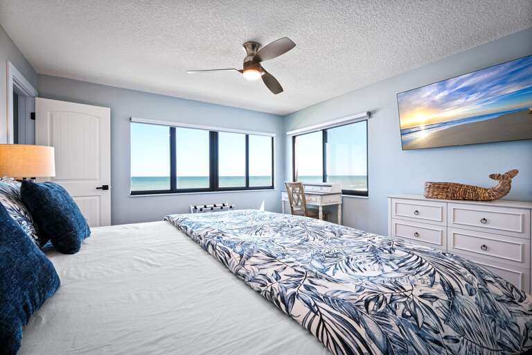 The luxurious master bedroom features a king bed and a stunning oceanfront view of New Smyrna Beach The luxurious master bedroom features a king bed and a stunning oceanfront view of New Smyrna Beach