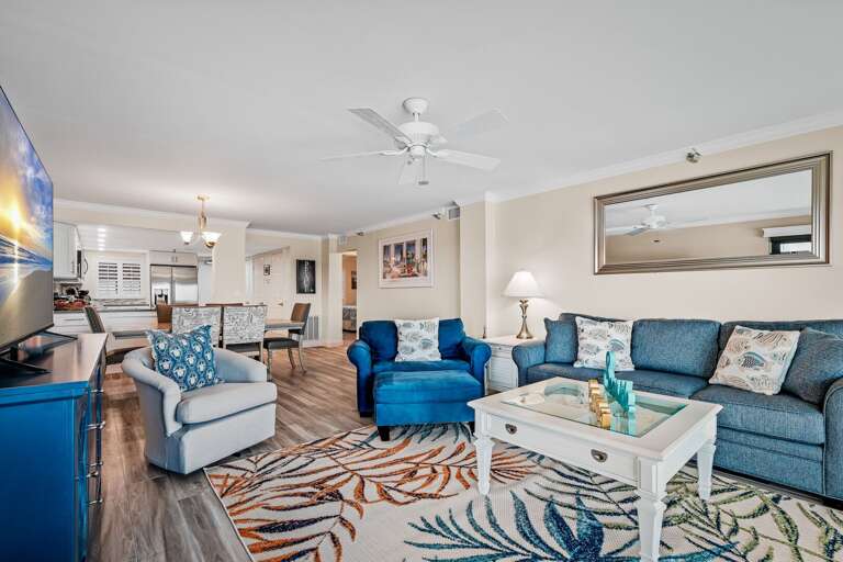 The spacious living room has comfortable seating, a large TV with cable, and a New Smyrna Beach view