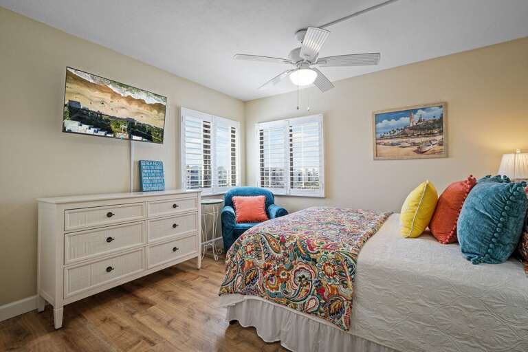 The bright guest bedroom features a comfortable queen bed and a mounted TV
