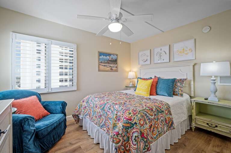 The bright guest bedroom features a comfortable queen bed and a mounted TV