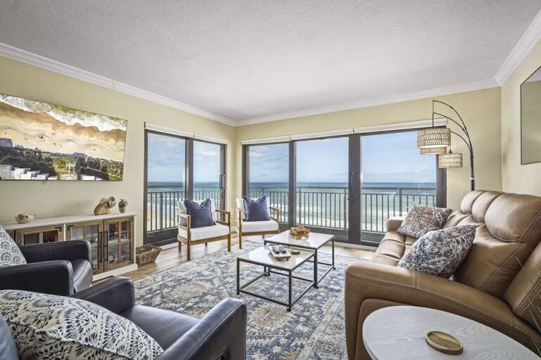 The comfortable, updated oceanfront living room features a large smart TV, zero-gravity reclining sofa, and reclining chairs, creating the perfect space to unwind while enjoying stunning beach views